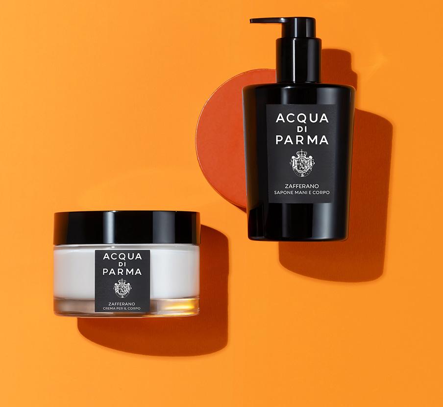 Imagen de una locion y una crema en un fondo de color naranja. ACQUA DI PARMA