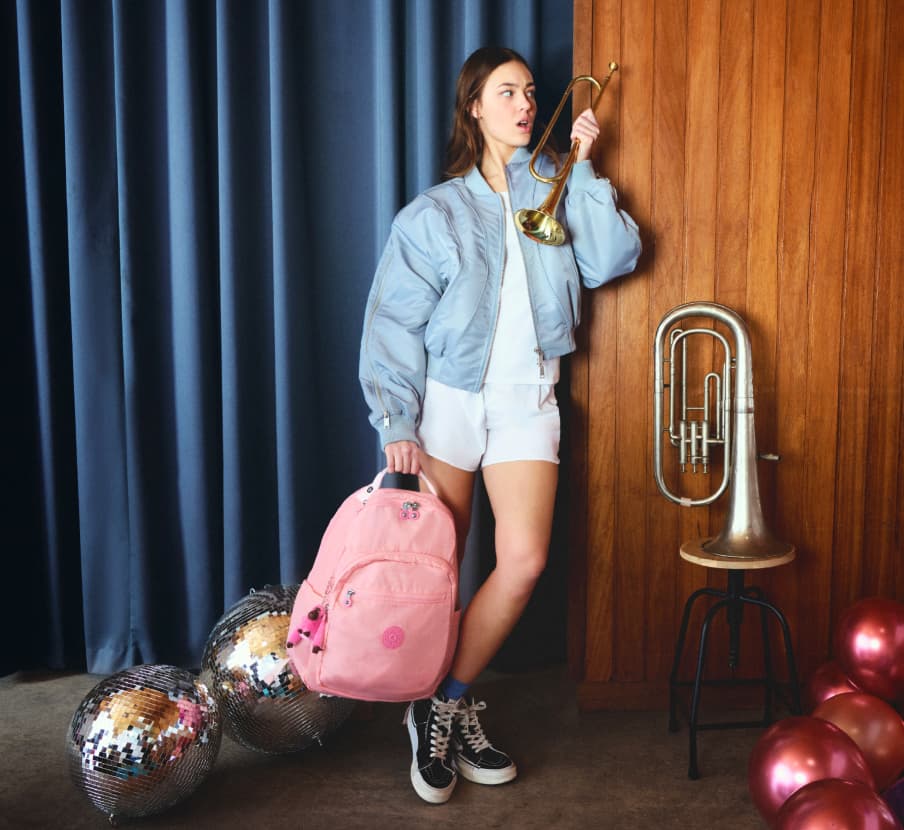 imagen de mujer con ropa blanca y mochila rosa de la marca KIPLING
