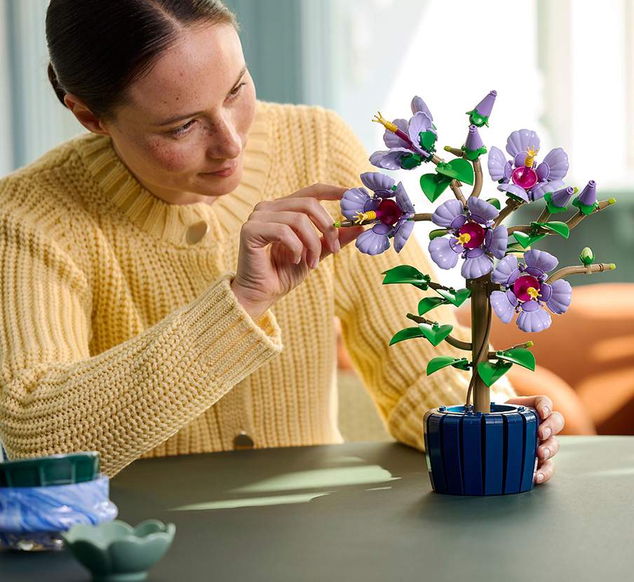 imagen de mujer con sueter amarillo y ramo de flores de lego de la marca LEGO