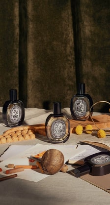 imagen 3 botellas de locion color gris con tapa mnegra en mesa de madera, DIPTYQUE