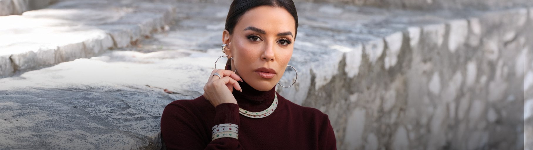 imagen de mujer con blusa vino y collar y pulceras plateadas de la marca APM MONACO