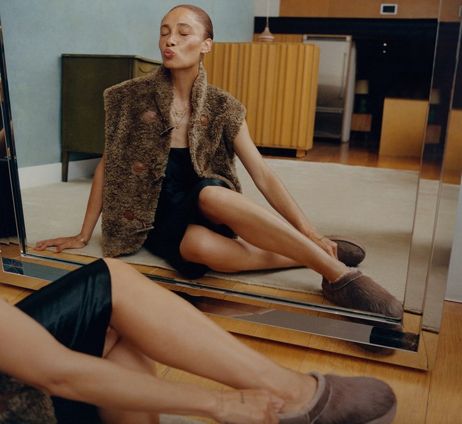 imagen de mujer con ropa color negra y cafe y sandalias cafes de la marca UGG