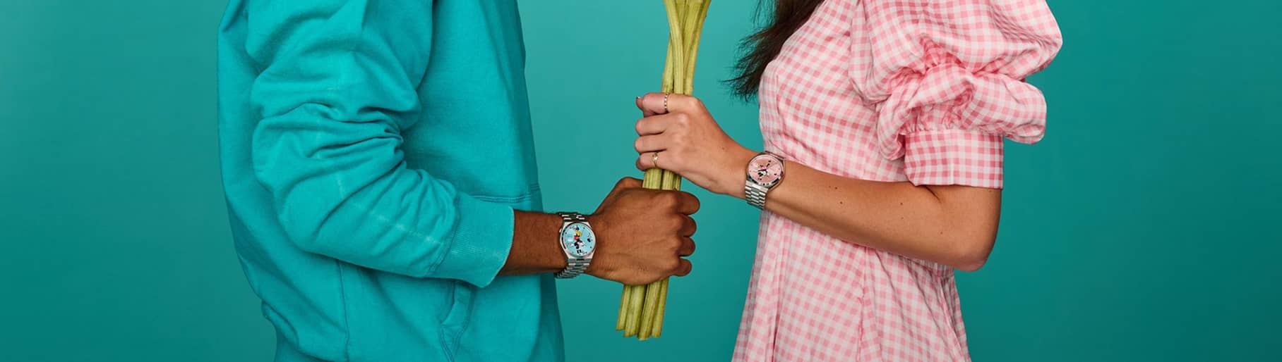 Imagen de una mujer y un hombre sosteniendo al mismo tiempo un ramo de flores, ambos llevan un reloj plateado con caratula de MICKY MAUSE, CITIZEN