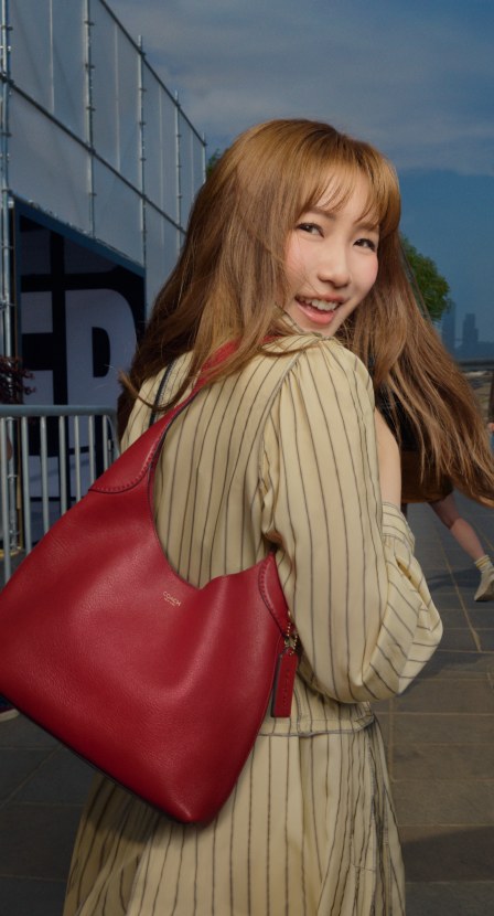 imagen de mujer convestido cafe y bolso rojo de la marca COACH