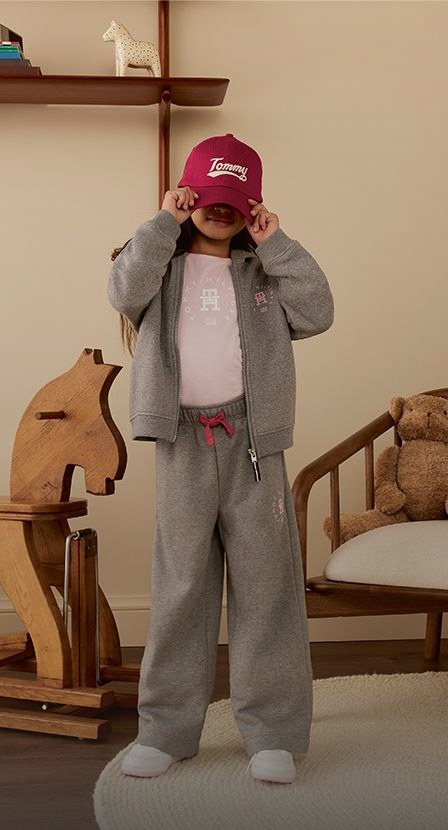 imagen de niña con pans gris y gorra roja de la marca tommy hilfiger
