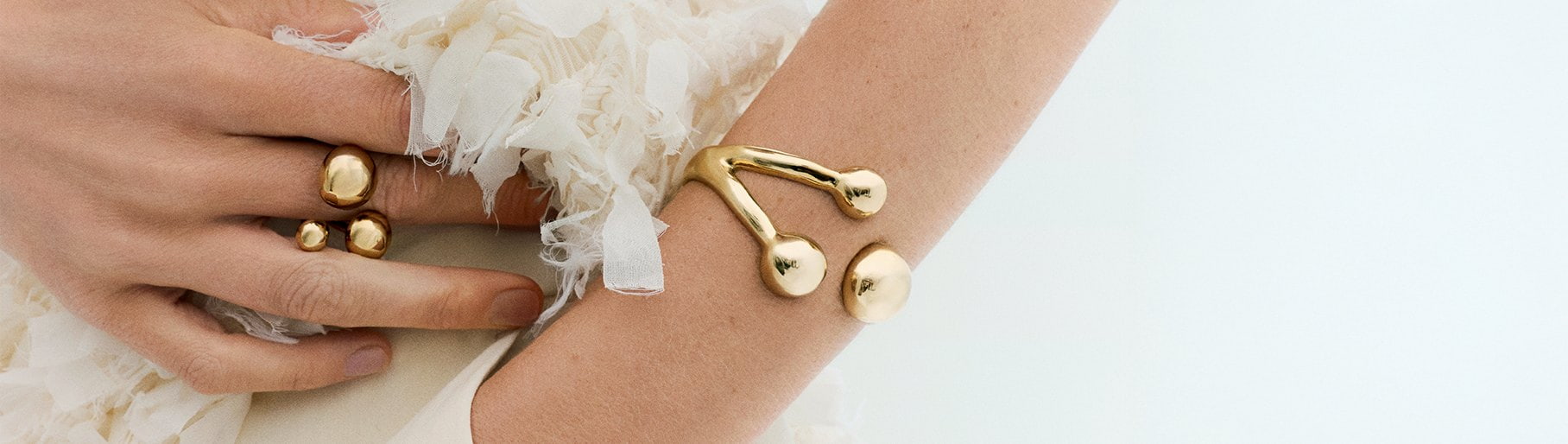 imagen de mujer usando pulcera y anillo dorados de la marca UNO DE 50