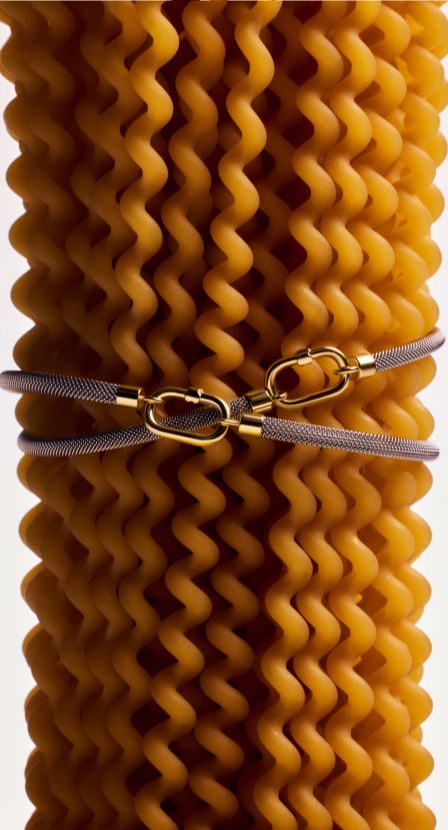 imagen de mujer de espaldas lleva en su pelo broches dorados con forma de flecha y un corazon de la marca TOUS