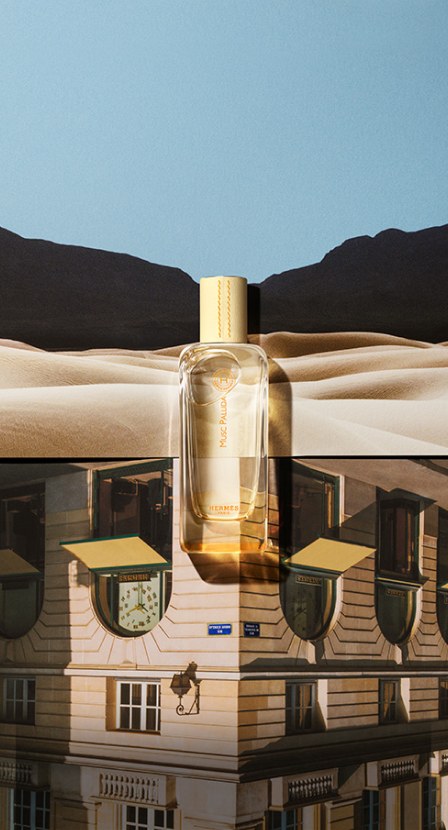 imagen de un frasco de perfume de la marca HERMES de fondo la imagen de un desierto y una edificio