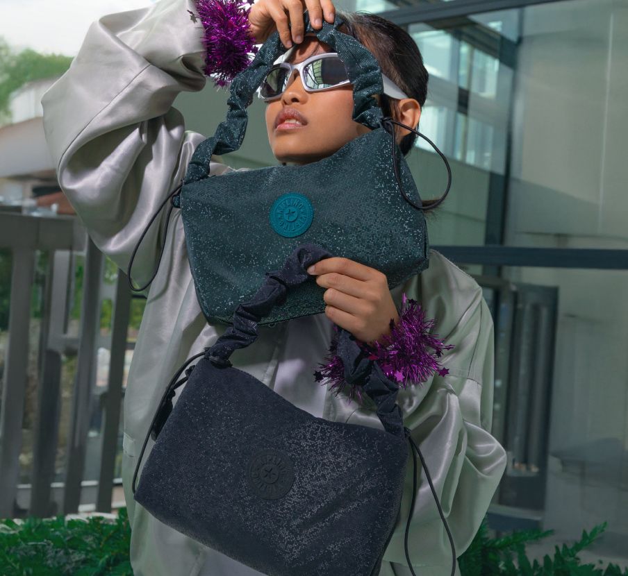 imagen de mujer con bolso negro y verde de la marca KIPLING
