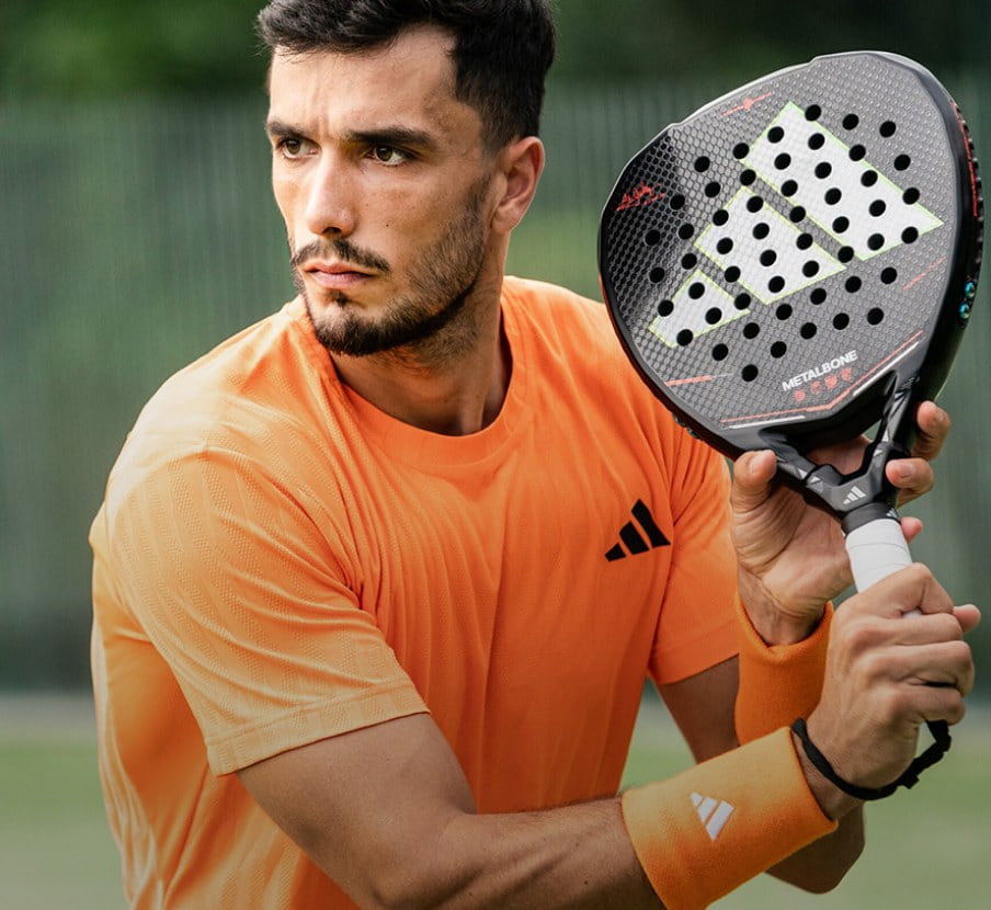 imagen de hombre con playera naranja y raqueta negra de TENIS Y PADEL