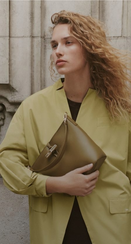 imagen de mujer con saco verde con bolso verde de la marca LONGCHAMP