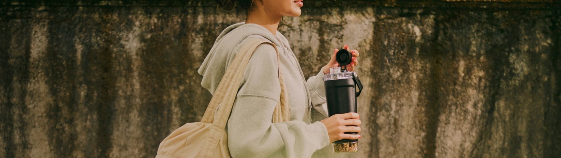 imagen de mujer con sudadera gris y termo negro de la marca STANLEY