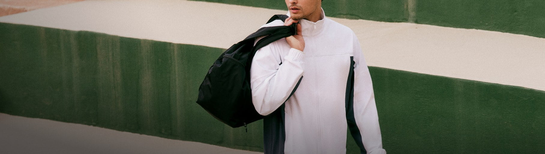 imagen de hombre con chamarra blanca y mochila negra de la marca VUORI  