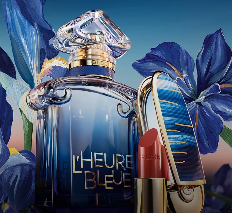 imagen de frasco de perfume azul, a lado un espejo y un labial de la marca GUERLAIN