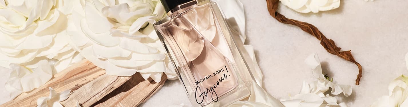 Imagen de una botella de pergume Gorgeous de la marca MICHAEL KORS sobre flores blancas, MICHAEL KORS Perfumes