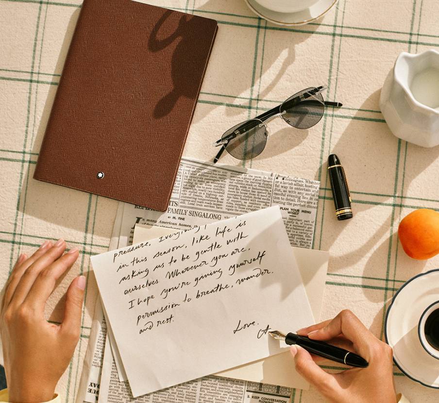 Imagen de una persona escribiendo una carta con una pluma negra, MONTBLANC