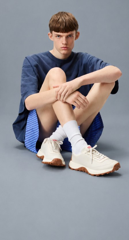 Imagen de niño con ropa azul y tenis blancos de la marca CAMPER