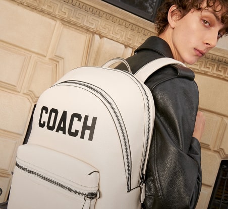 imagen de dos hombre con mochila blanca COACH