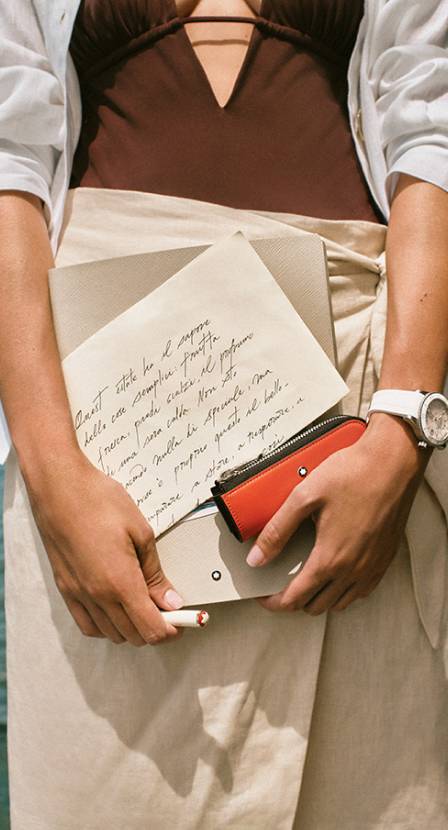 Imagen de una mujer que sostiene una libreta y una cartera, MONTBLANC