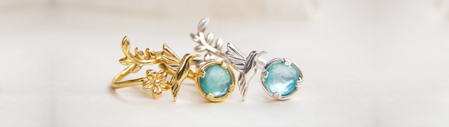 imagen de un par de aretes uno de color dorado y otro de color plateados ambos con una piedra azul y figura de pajaro, TANYA MOSS