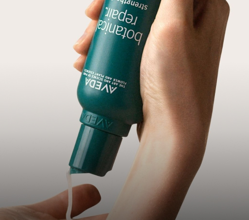 botell a de shampoo de color verde en manos de una mujer, dice en letras blancas, Botanical repair de la marca AVEDA