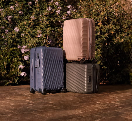 imagen de 3 maletas rigidas una azul una plateada y una gris TUMI