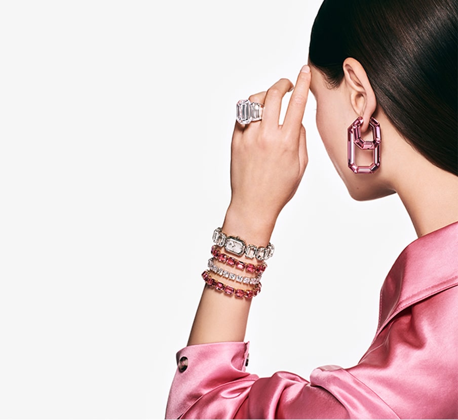 Imagen una mujer con blusa rosa y joyeria de la marca SWAROSVKI
