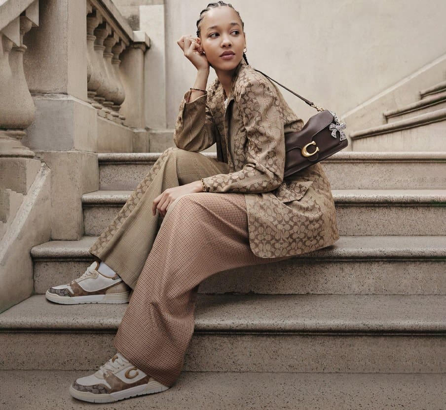 imagen de mujer con ropa y boso cafe de la marca COACH