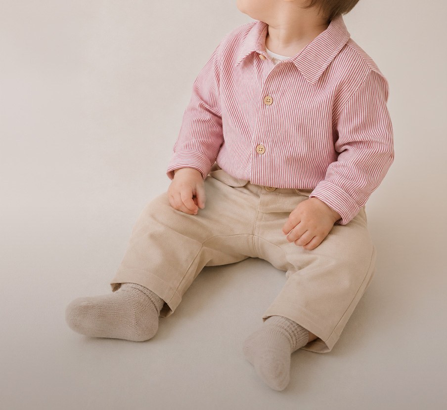 imagen de niño con camisa a rayas rojas con blanco y pantalon cafe de la marca PRIMMI 