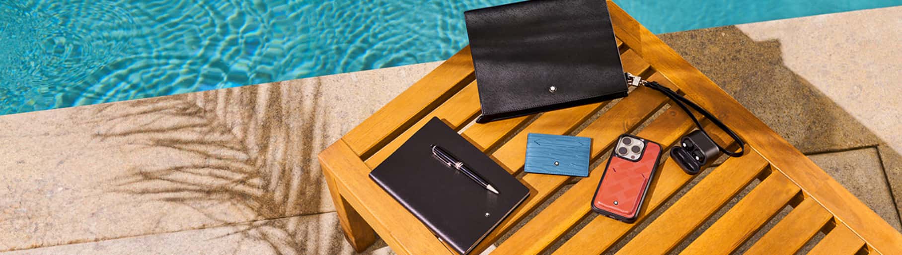 Imagen de una banca de madera, en la cual hay accesorios de la marca MONTBLANC, MONTBLANC