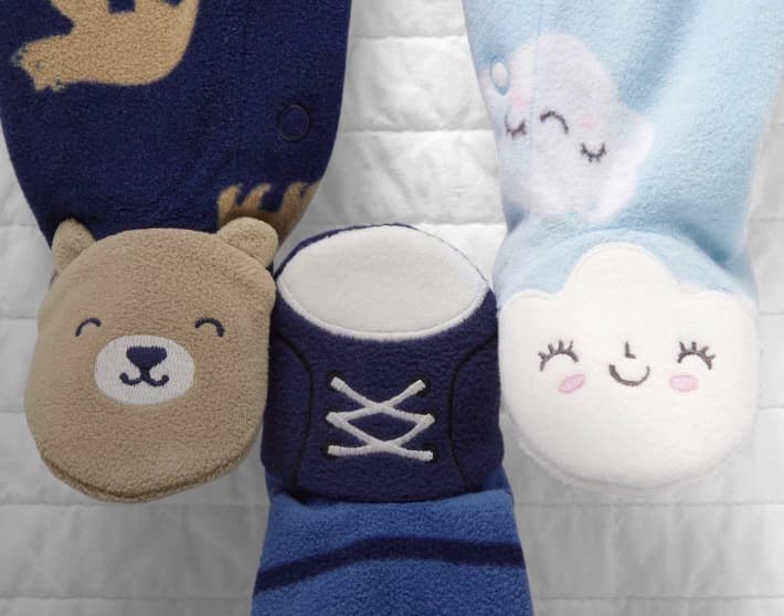 Parte inferior de tres mamelucos distintos. Uno con una cara de oso, otro con una nube sonriente y el último con un tenis. CARTER'S