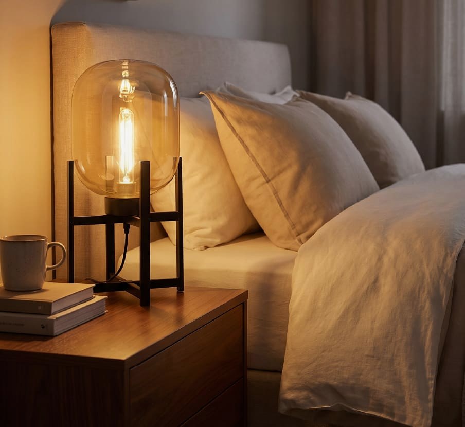imagen de una cama y a lado una lampara de mesa de la marca CLASS ILUMINACION