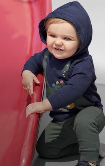 Bebé usando un conjunto de pants verde y sudadera azul con estampado de dinosaurio. CARTER'S