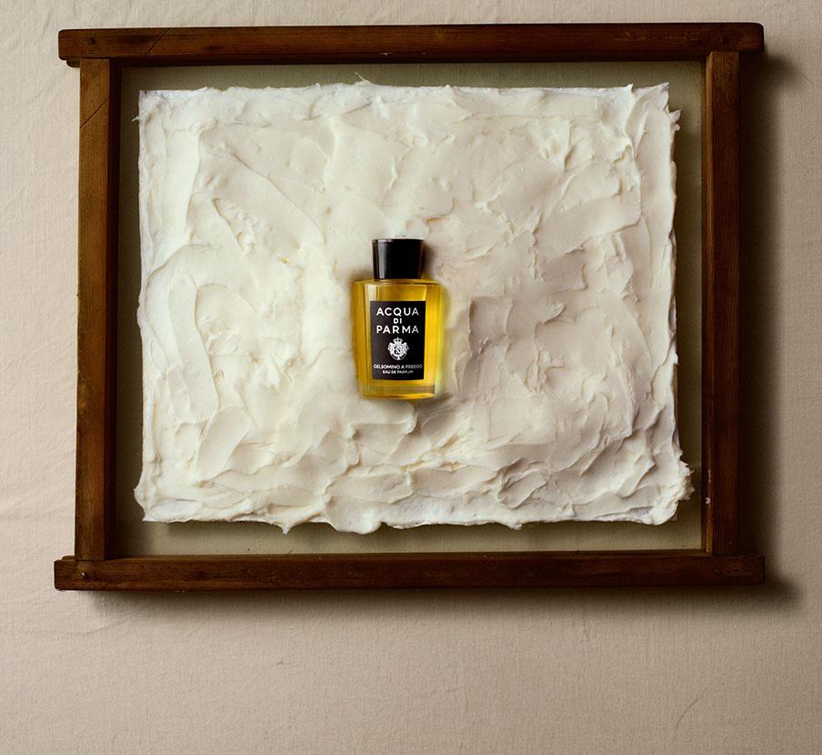 Imagen de de un frasco de perfume color amarillo en medio de un cuadro. ACQUA DI PARMA