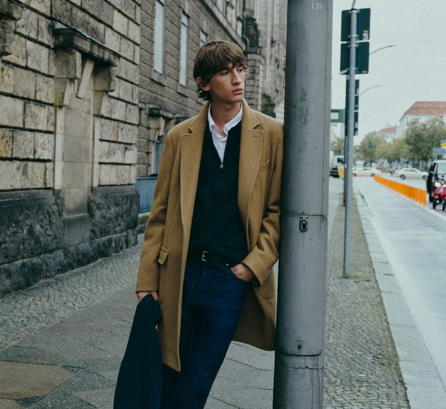 imagen de hombre con abrigo cafe y ropa negra de la marca SCALPERS