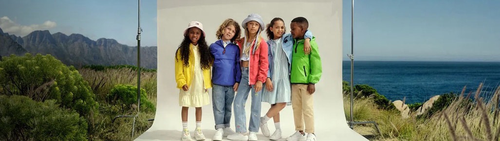 imagen de cinco niños, una niña con ropa amarilla, niño con chemarra morada, niña con chamrra coral, niña con vestido azul y rayas balncas y niño con chemarra verde, TOMMY HILFIGER