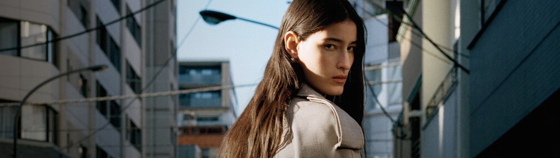 imagen de mujer con gabardina cafe de la marca Mango