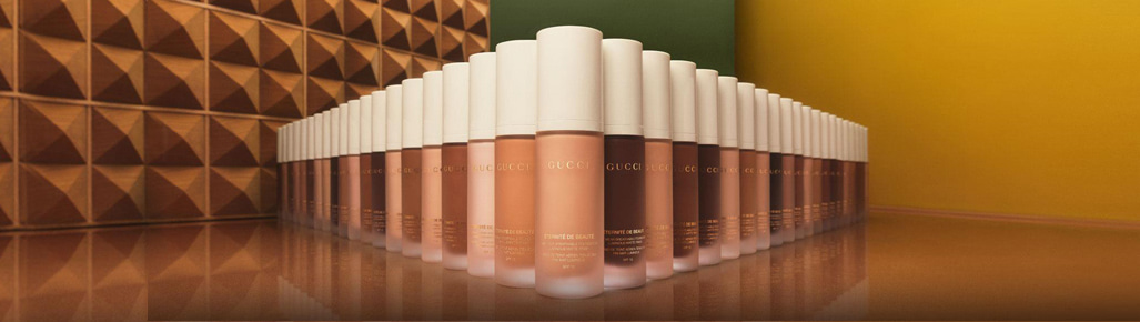 Imagen de muchos frascos de bases de maquillaje acomodadas de forma triangular de la marca GUCCI, GUCCI