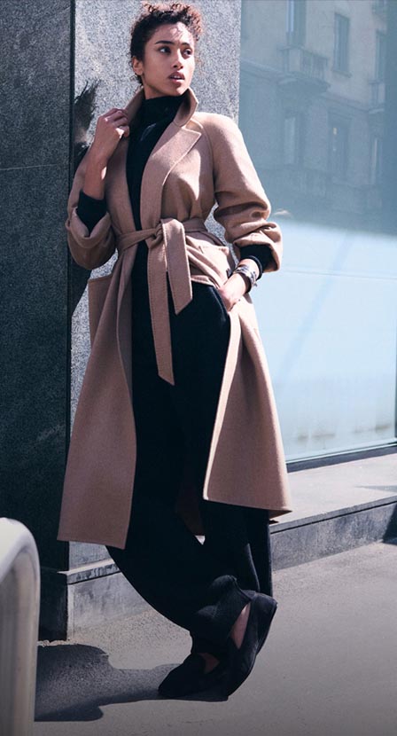 Imagen de mujer con ropa negra y saco cafe de la marca MAX MARA