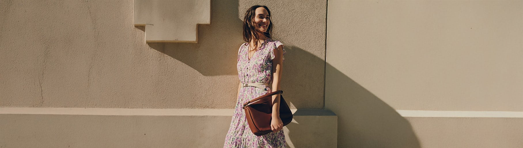 Imagen de mujer con vestido de flores y bolso cafe de la marca JULIO