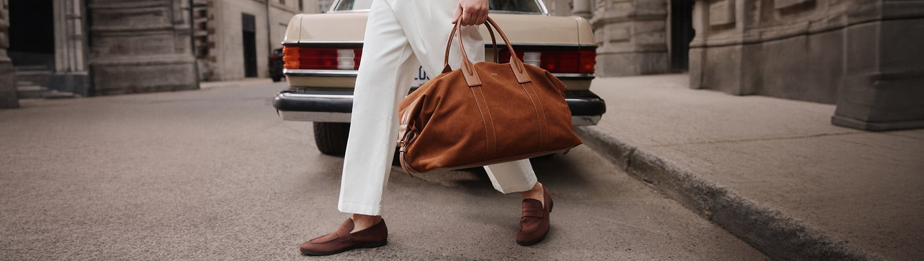 Imagen de hombre con zapatos y bolso cafe y pantalon blanco de la marca ALDO
