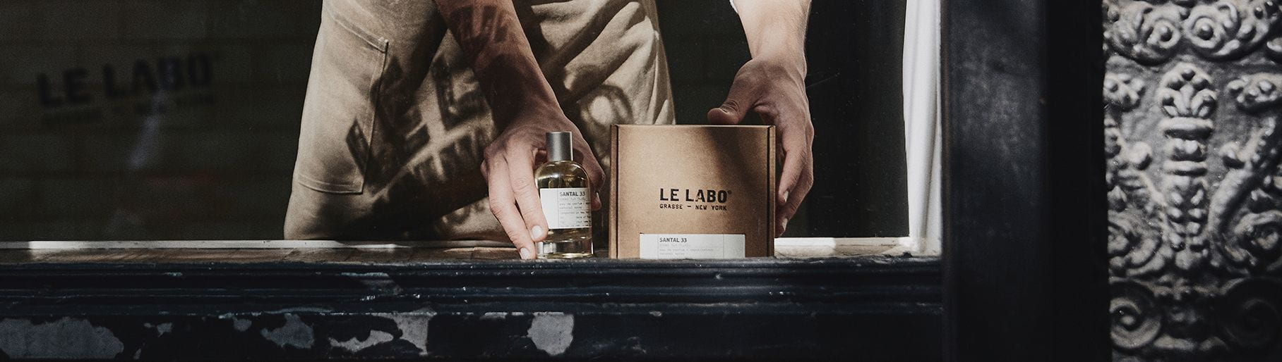 Imagen de un hombre sosteniendo una caja y un frasco de perfume LE LABO