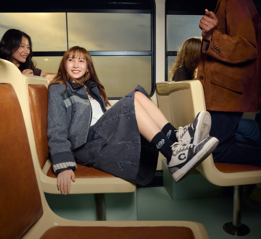 imagen de mujer en el subterraneo con tenis negros con blanco de la marca COACH