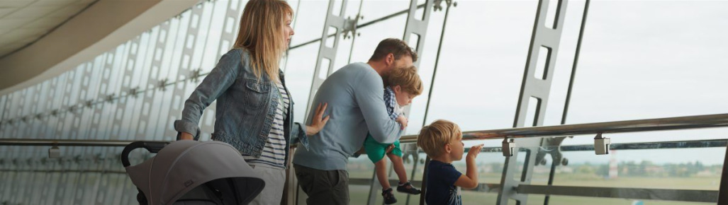 una familia de un hombre, dos niños y una mujer, viendo por un ventanal .