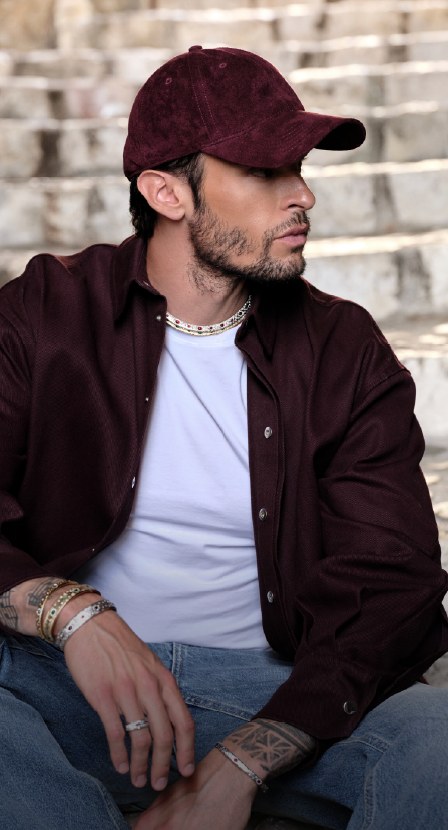 imagen de hombre con gorra y camisa vino con joyeria plateada
