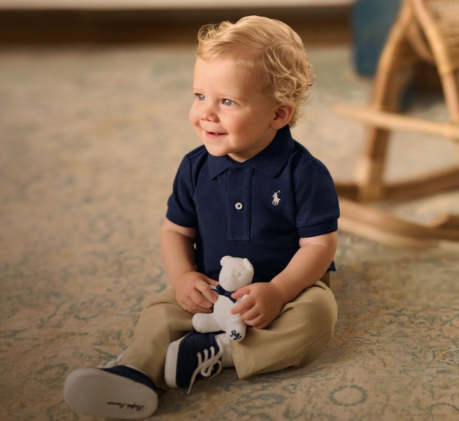 imagen de bebe con playera azul, tenis azules y pantalon cafe de la marca RALPH LAUREN