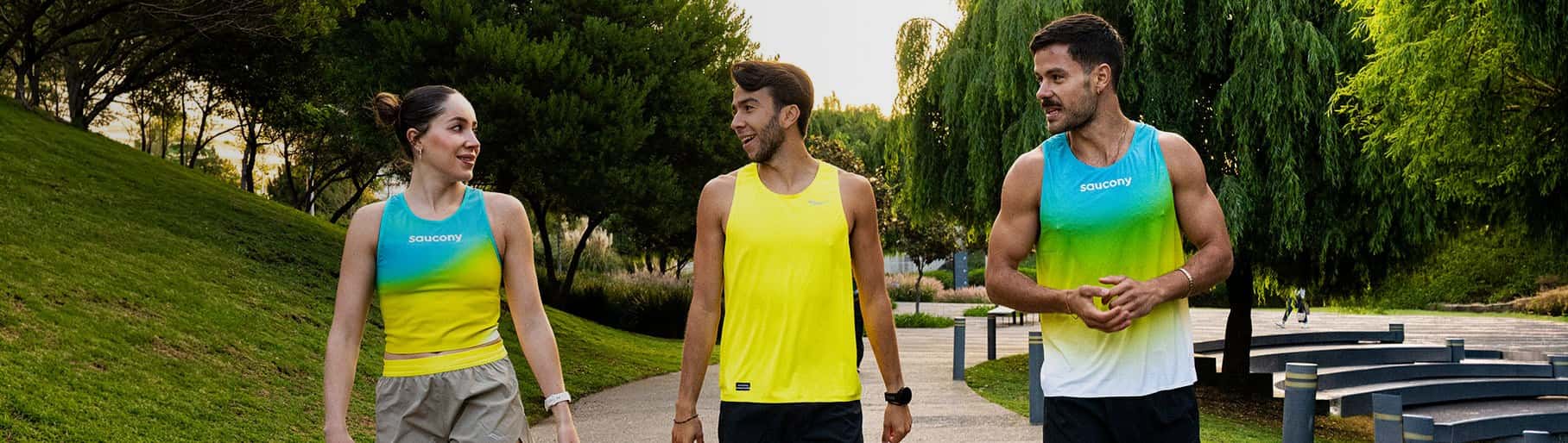 imagen de 2 hombres y una mujer con playeras amarillas con azul de la marca SAUCONY