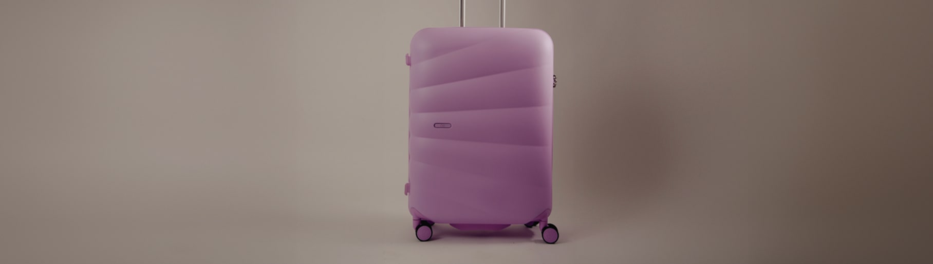 imagen de una maleta grande para vieje con llantas de color rosa de la marca CLŌE 