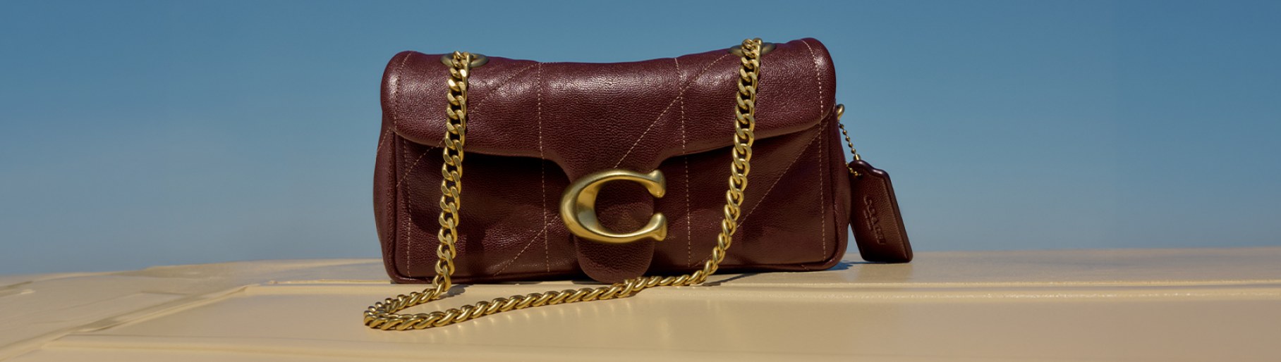 imagen de bolso guinda con dorado de la marca COACH