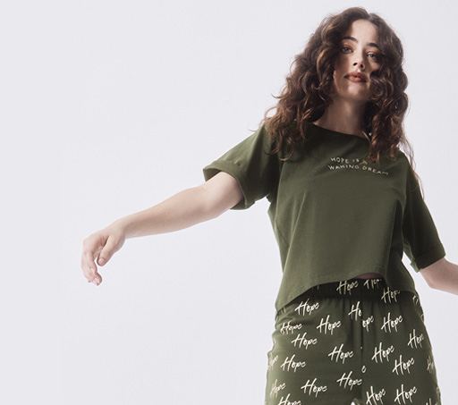 Mujer usando playera y pantalon para dormir color verde con estampado de letras blancas. SKINY